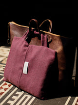 Reisedecke in aubergine aus Merino gewebt und gut als Reiseaccessoire mit Kissenbezug und Griff für Handgepäck in luxuriösem Design mit Nachhaltigkeit gefertigt als das perfekte Geschenk für Kreuzfahrten und Städtereisen und in Gaskrise bei Energie Sparen und Heizen im kalten Winter