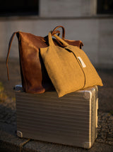 Reisedecke in gelb grau aus Merino gewebt an Rimowa Koffer und gut als Reiseaccessoire mit Kissenbezug und Griff für Handgepäck in luxuriösem Design mit Nachhaltigkeit gefertigt als das perfekte Geschenk für Kreuzfahrten und Städtereisen und in Gaskrise bei Energie Sparen und Heizen im kalten Winter