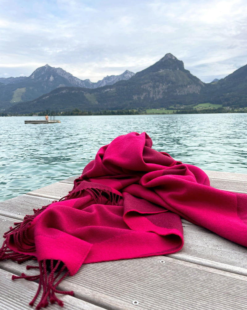 Schal und Reisedecke auf Steg am Wolfgangsee  in pink aus Merinowolle gewebt in Pink und gut als Accessoire für Reise in Auto und Oldtimer in luxuriösem Design mit Nachhaltigkeit und handgefertigt als das perfekte Geschenk für den Strandurlaub und in Gaskrise bei Energie Sparen und Heizen im kalten Winter