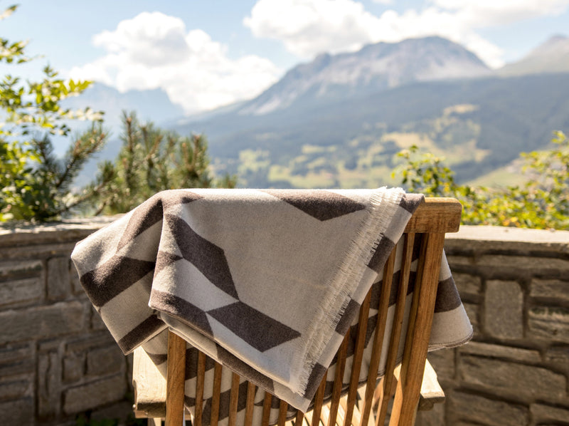 Wolldecke in grau weiss Muster aus extra feinem Merino gewebt als zeitloses Plaid Interieur Accessoire für Zuhause in luxuriösem Design und Nachhaltigkeit und das perfekte Geschenk für jedes Sofa und vor Kamin im Chalet